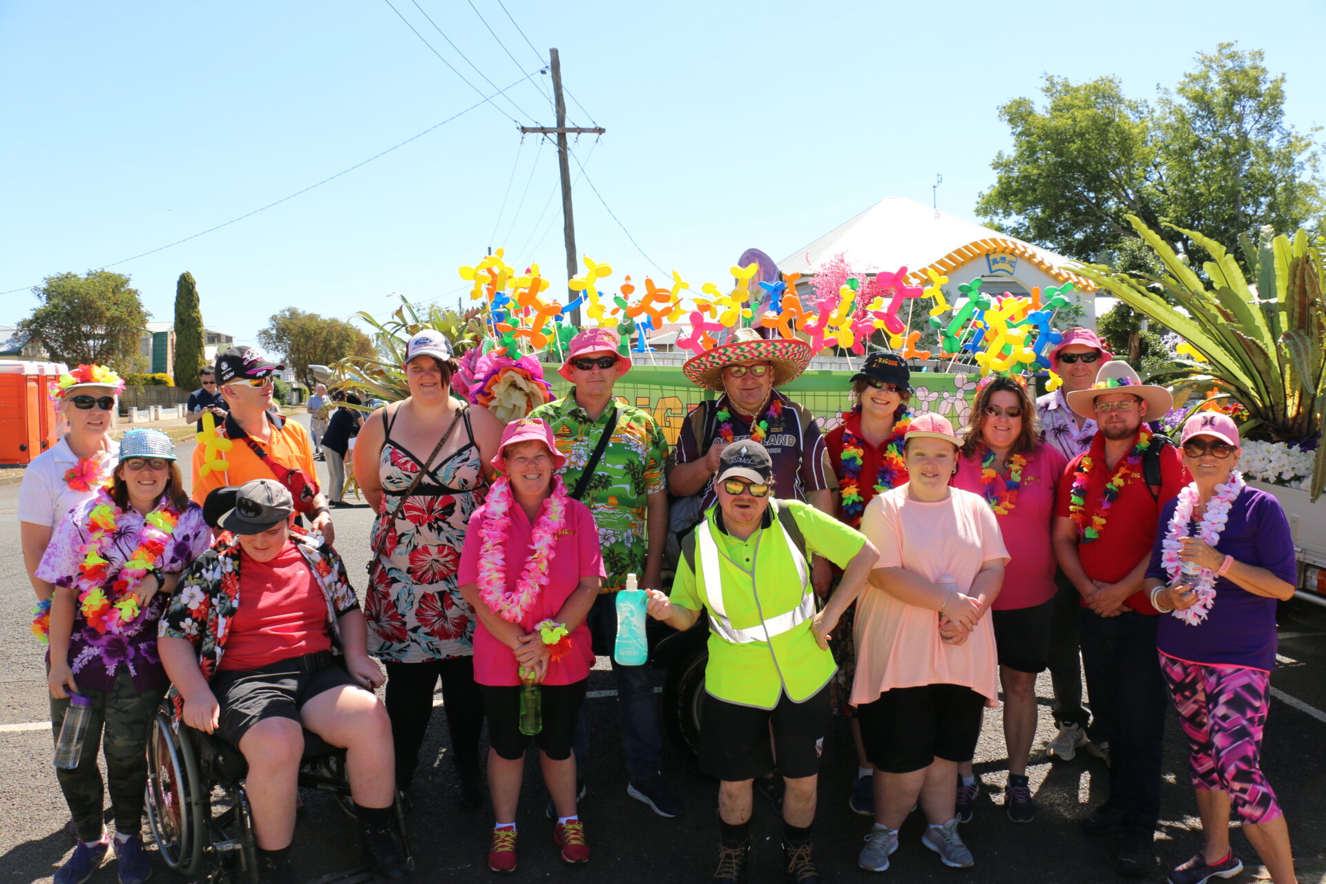 A group 0f 13 people in colourful shirts and flowers preparing for the Toowoomba Carnival of Flowers Parade.